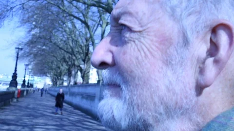 Hand held close up of old man with wrinkles looking at the Thames on a cold day Stock Footage 98723985