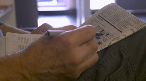 Hand held close up of a senior hand working a crossword puzzle in a newspaper Stock Footage 61493688