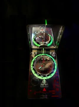 Hand-held compass at night with glowing dial Stock Photos