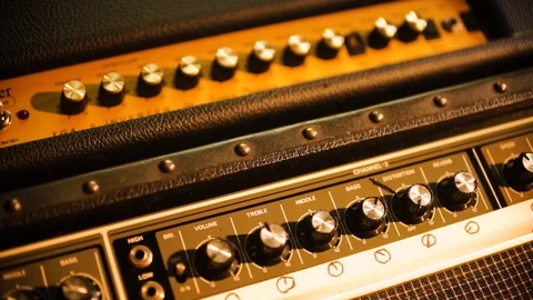 Hand Held Extreme Close Up of Guitar amp control knobs basking in warm Video stock 102828222