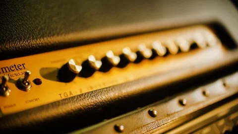 Hand Held Extreme Close Up of Guitar amp control knobs basking in warm Video stock 102828351