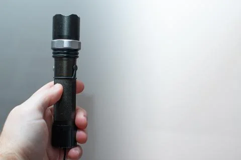 Hand-held flashlight in a man's hand Stock Photos