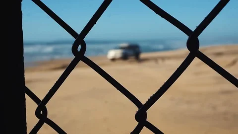 Hand held focus pull through chain link boarder wall at Tijuana boarder Stock Footage 99998549
