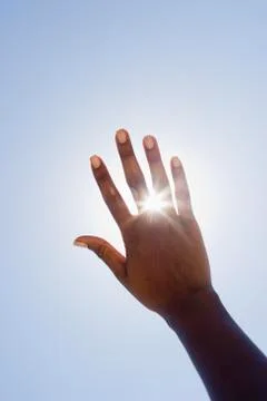 Hand held up in front of sunshine Stock Photos