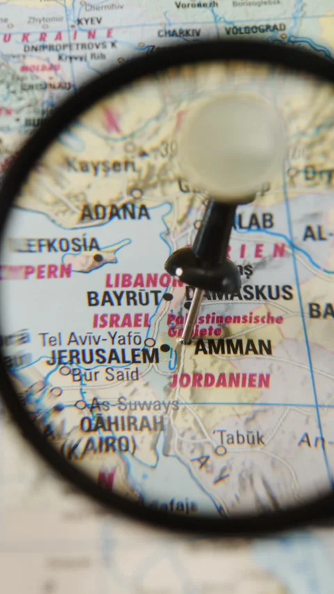 Hand-held magnifying glass highlights location on paper map of Amman Stock Footage 341273084