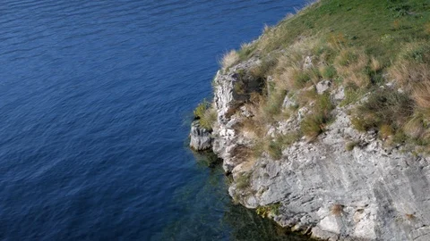 Hand held medium shot of a cliff and the calm sea with its gentle waves Stock Footage 119422366