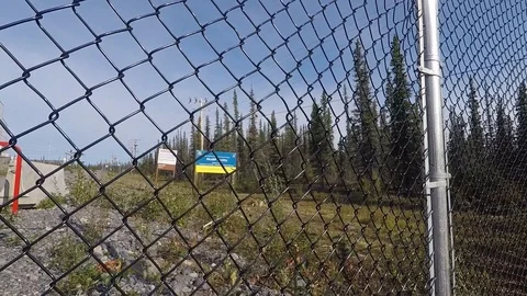 Hand held panning reveal of chain link fence and danger warning signs at Stock Footage 115486091