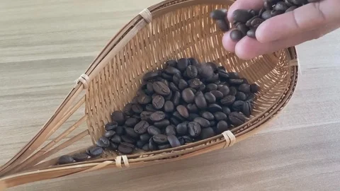 Hand held raw coffee beans tossed into a wooden basket Closeup video slow motion Stock Footage 123758916