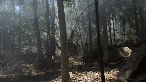 Hand-held shot of Aztecs running through the woods with spears as smoke takes Stock Footage 202909788