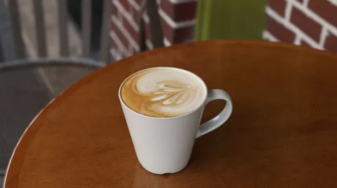 Hand held shot of latte coffee drink on table at cafe Stock Footage 45479862