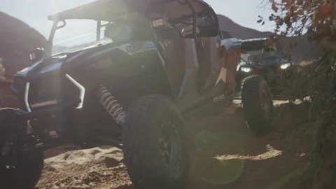 Hand held shot of UTVs driving through red desert landscape on off road trail Stock Footage 234034712