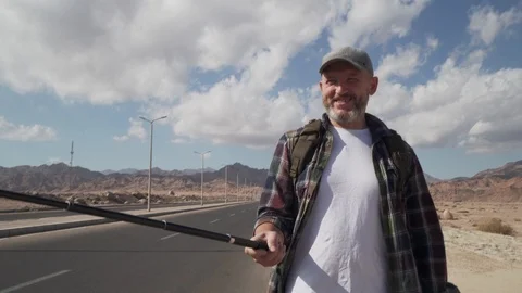 Hand-held shot of walking senior traveler male shooting himself with monopod Stock Footage 100883677
