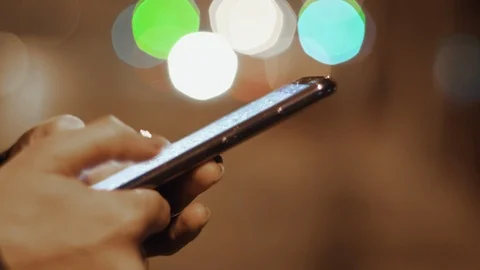 Hand Held Shot Of Woman Using Smartphone At Night Close Up Video stock 102774644