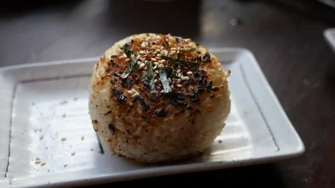 Hand held slow motion close up of grilled rice ball with furikake seasoning Stock Footage 155776041