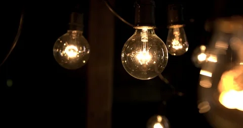 Hand held slow motion group of light bulbs in dark barn Stock Footage 98357642