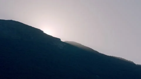 Hand-held sun about to pop out from behind a mountain Stock Footage 196813463