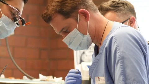 Hand held video of dentists operating Stock Footage 127000944