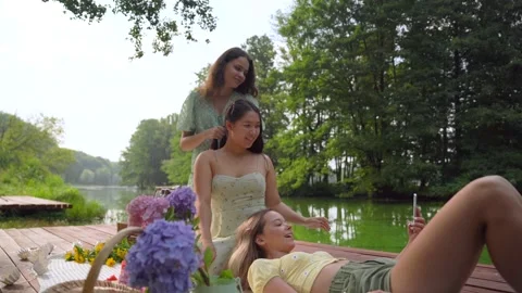 Hand-held of young multinational female doing selfie at picnic time Low angle Stock Footage 158886635