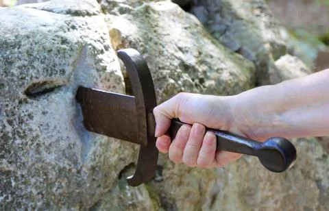 Hand of a hero pulling the legendary medieval sword Excalibur from the stone Fotos Stock