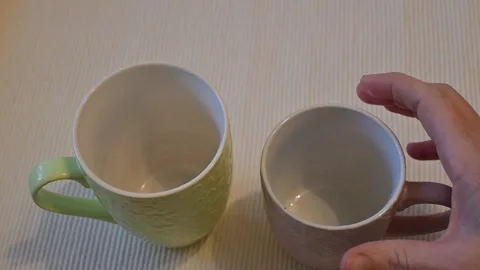 Hand hesitating to take mug on white background Stock Footage 336061988