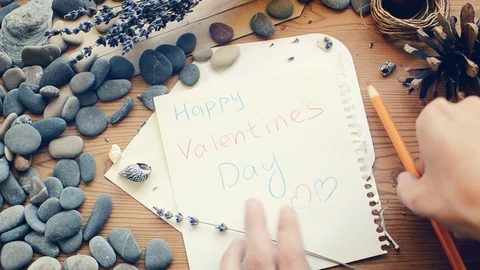 A hand is hiding a note in an envelope: Happy Valentine's Day. Stock Footage 98139991