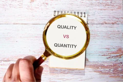 Hand highlights Quality vs Quantity on a notebook. Key business strategy comp Stock Photos