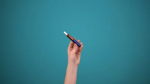 Hand hold e-cigarette isolated on blue background, smoking device Stock Footage 129058141