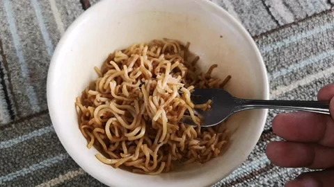 Hand hold a fork while twist hot fried noodles in a bowl Stock Footage 130427952