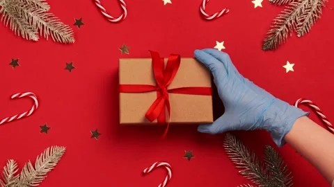 Hand hold gift box in protective gloves  COVID 19. Christmas 2021. Pandemic Stock Footage 144136392