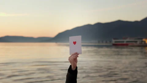 Hand hold Love letter in front of lake and mountains in sunset. Valentine's day Vídeos de archivo 229508434