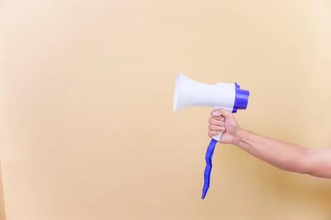 A hand hold megaphone speaker isolated on beige background Stock Photos
