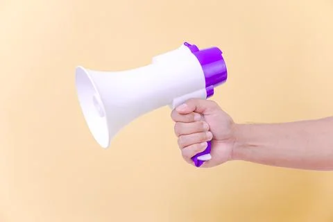 A hand hold megaphone speaker isolated on beige background Stock Photos