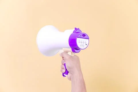 A hand hold megaphone speaker isolated on beige background Stock Photos
