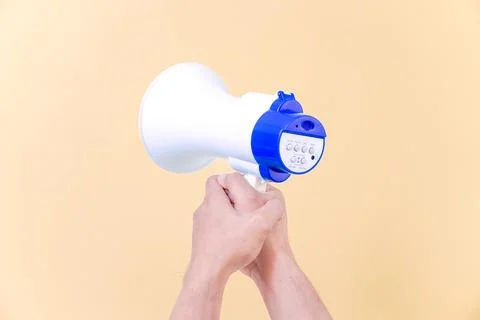 A hand hold megaphone speaker isolated on beige background Stock Photos