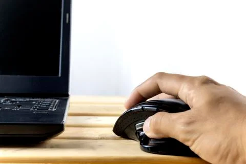Hand hold mouse control laptop on wood table. With copy space for text or des Stock Photos