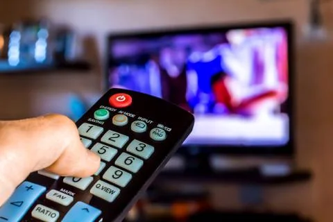 Hand hold the remote control to change channels on Tv Stock Photos
