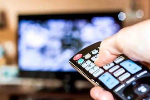 Hand hold the remote control to change channels on Tv Stock Photos