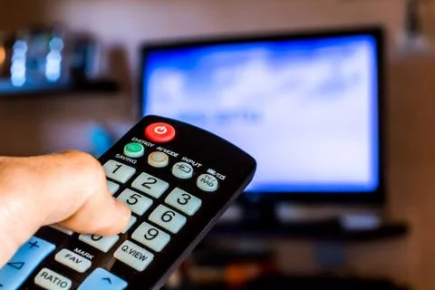 Hand hold the remote control to change channels on Tv Stock Photos
