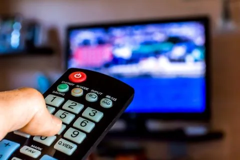 Hand hold the remote control to change channels on Tv Stock Photos