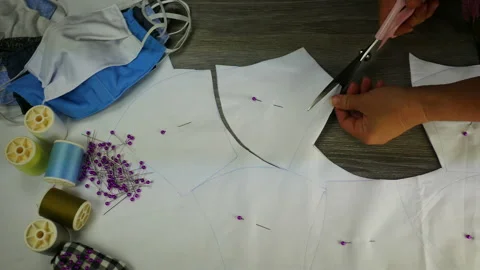 Hand hold scissors cut white cloth pattern, prepare to sew protective mask ,  Stock Footage 131339331