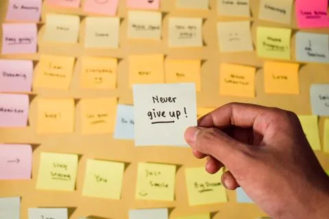 Hand hold sticky notes with words Never Give Up. Motivational words for personal Stock Photos
