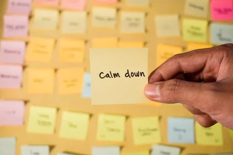 Hand hold sticky notes with words Calm Down. Motivational words for personal Stock Photos