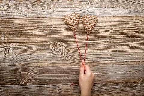 Hand hold two gingerbread in the form of hearts on red thread wooden background Stock Photos