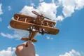 The hand hold a wood airplane on the cloud background Photo