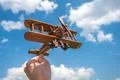 The hand hold a wooden plane on the background of the cloud Photo