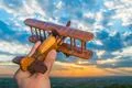 The hand hold wooden plane on the background of a sky Photo