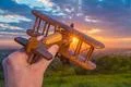 The hand hold wooden plane on the background of a sunset Photo