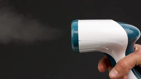 Hand hold working portable clothes steamer for clothes on a black background Video stock 156474668