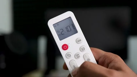 A Hand Holding AC Remote turning on the AC and decreasing the temperature Stock Footage 334000014