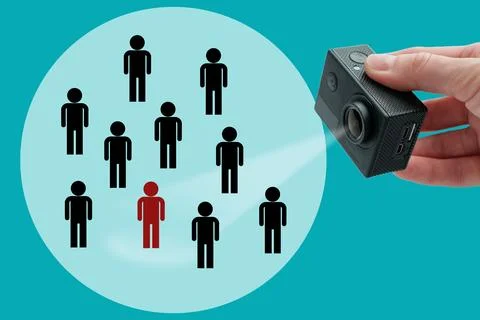 Hand holding an action camera pointing at a group of human icons with one h.. Foto stock